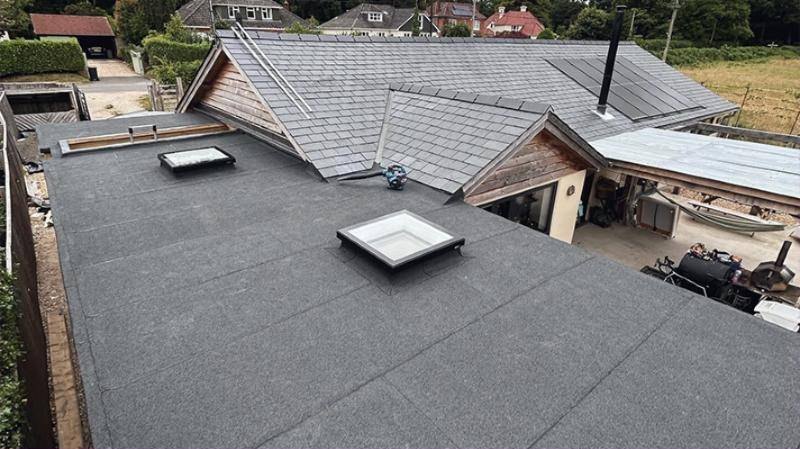 Three-layer torch-on felt flat roof with rooflights beside a slate pitched roof