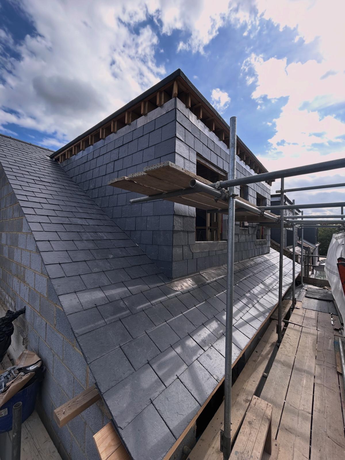 Loft conversion dormer with vertical slate cladding on its face and cheeks above a natural slate pitched roof
