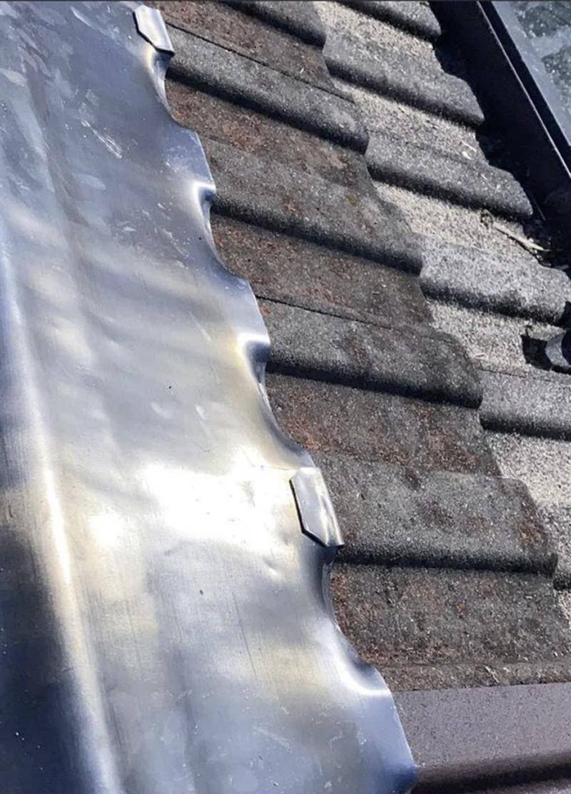 Close-up of lead flashing carefully dressed over the profile of interlocking roof tiles